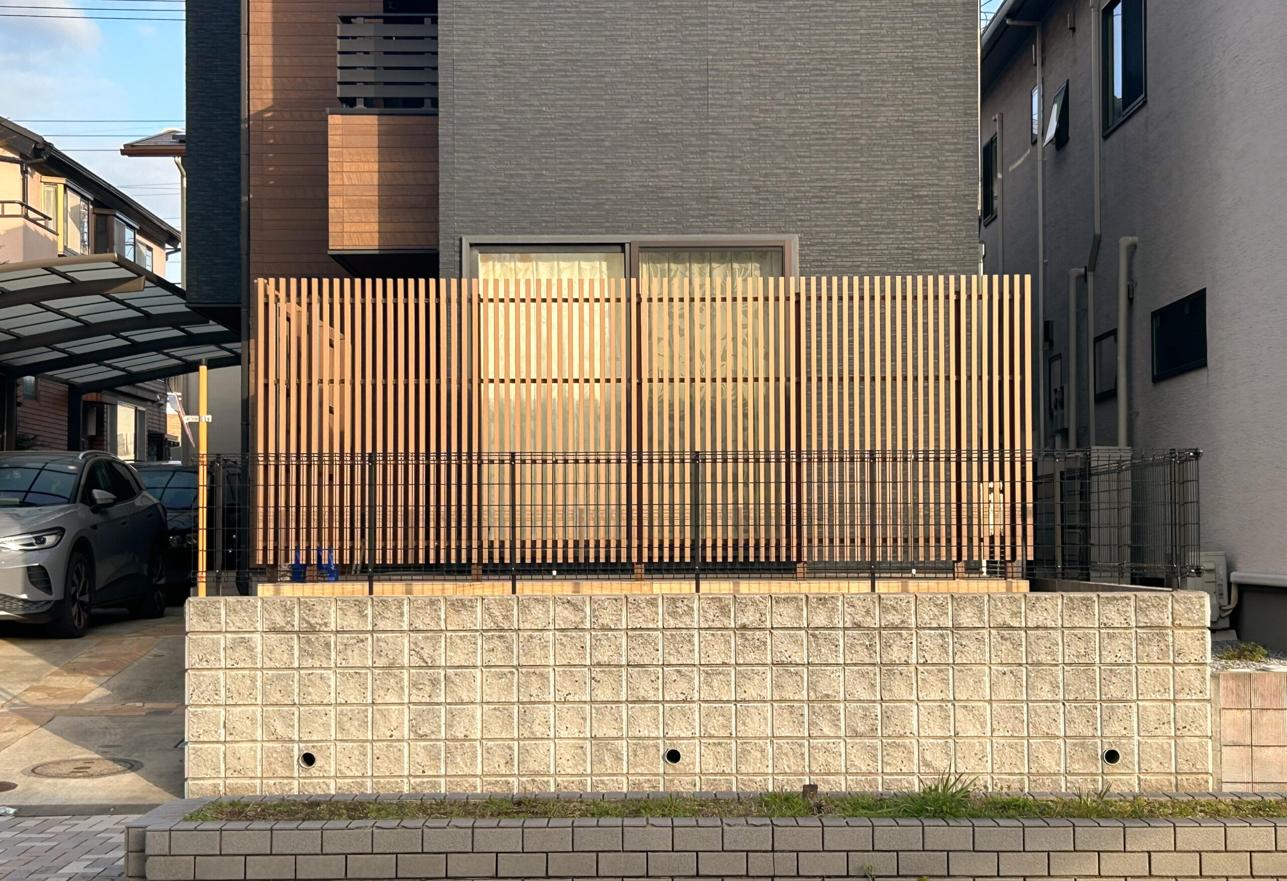 木製ルーバーで道路からの視線をやわらげた、隣家と近接する都市部の住宅外観
